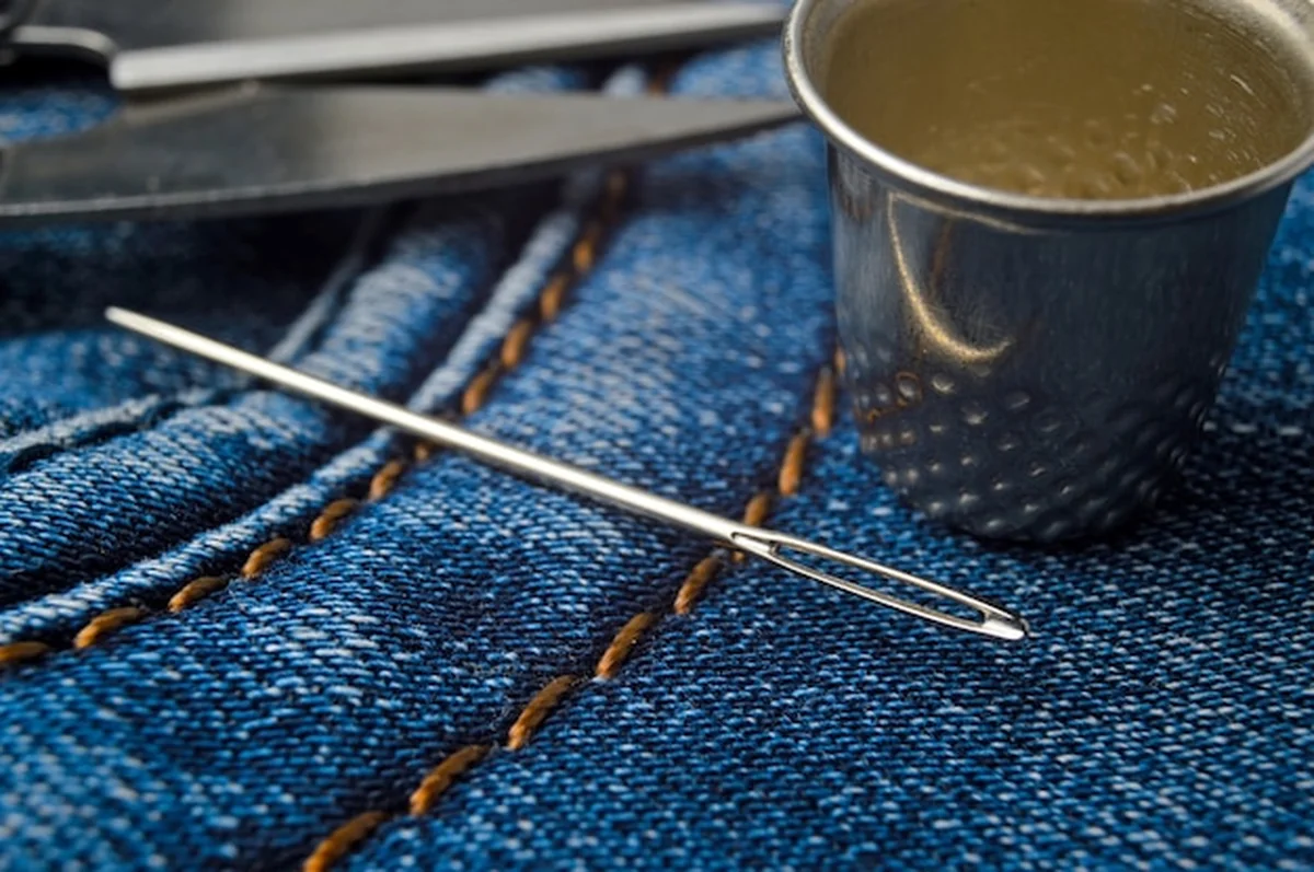 Igła z nicią przyszywająca dżinsowy materiał