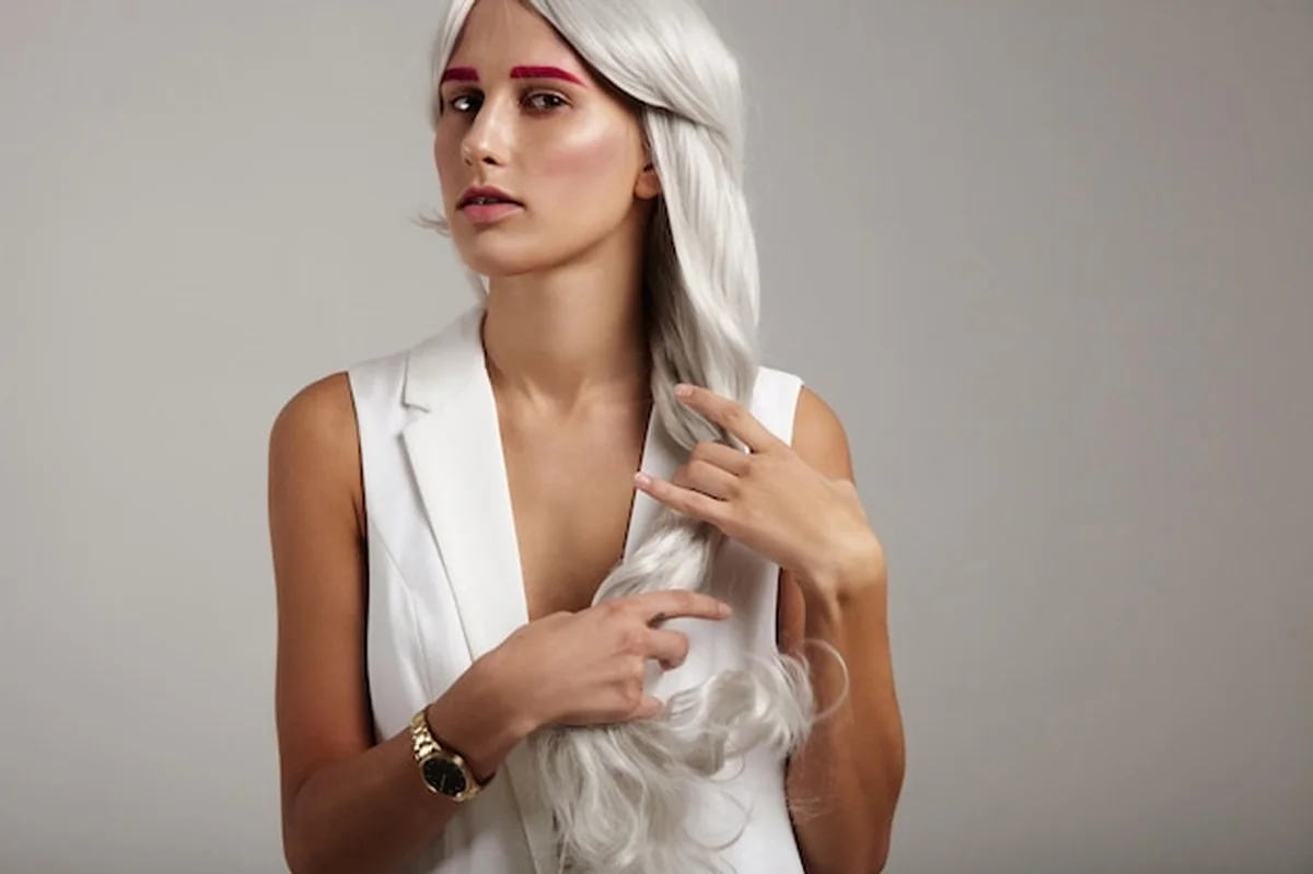 Kobieta delikatnie dotyka swoich siwych włosów