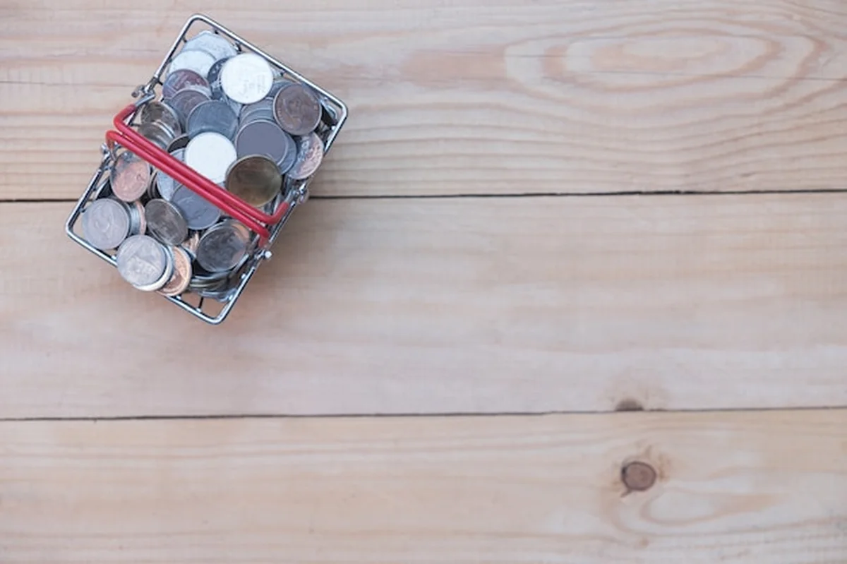 Dużo monet w koszyku na drewnianym stole