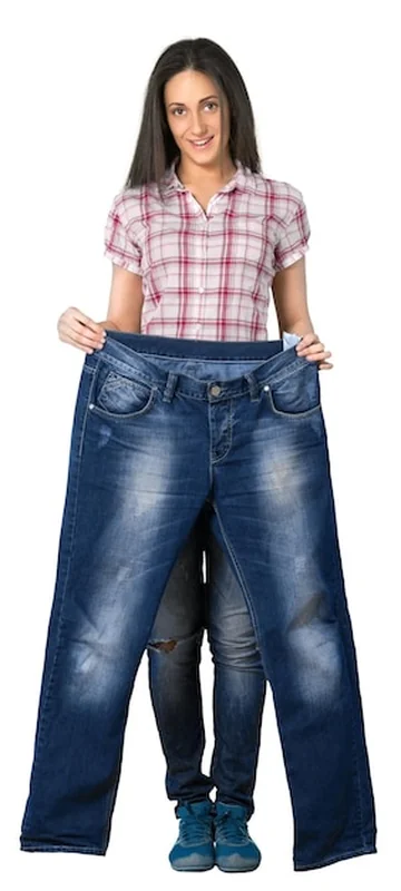 Młoda kobieta trzyma za duże dżinsy