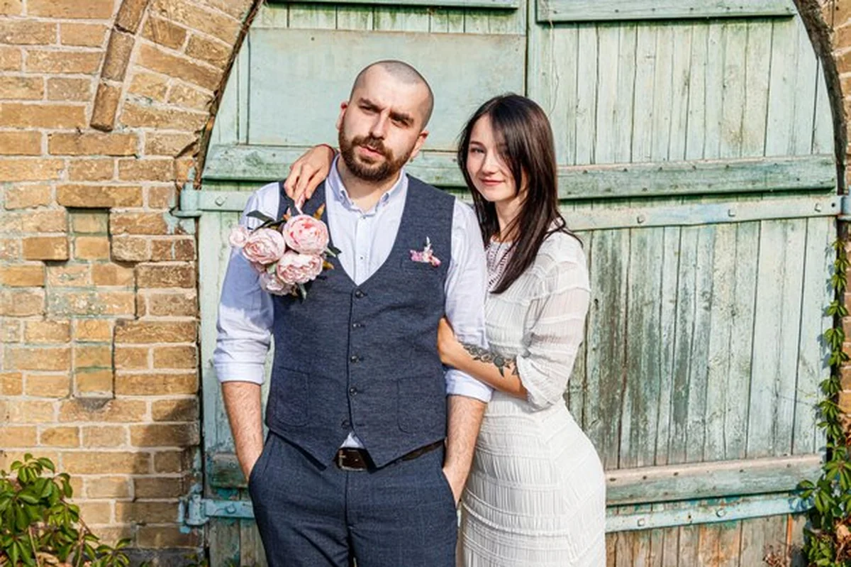 Piękna dziewczyna w białej sukience i facet przy starej ceglanej bramie