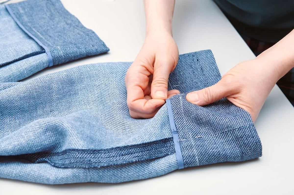 Krawiec robi oznaczenia kredą na nogawce spodni