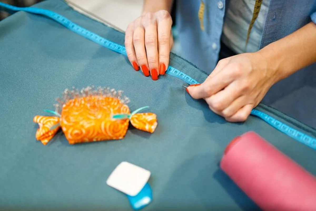 Krawcowa mierzy materiał w warsztacie tekstylnym