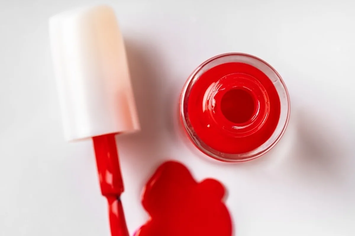 Kałuża rozlanego lakieru do paznokci na białym podłożu