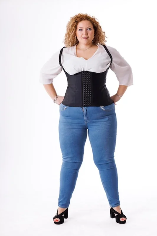 Modelka w ubraniach dżinsowych i białej koszuli na białym tle z nadwagą kobiecego ciała