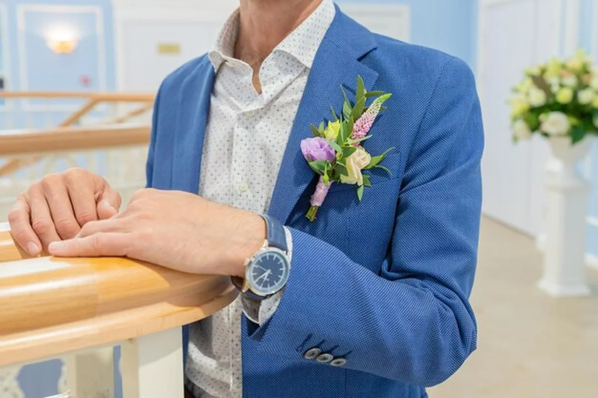 Mężczyzna w garniturze z butonierką na niebieskiej marynarce