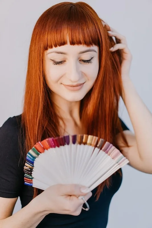 Kobieta z czerwonymi włosami badająca próbki kolorów włosów