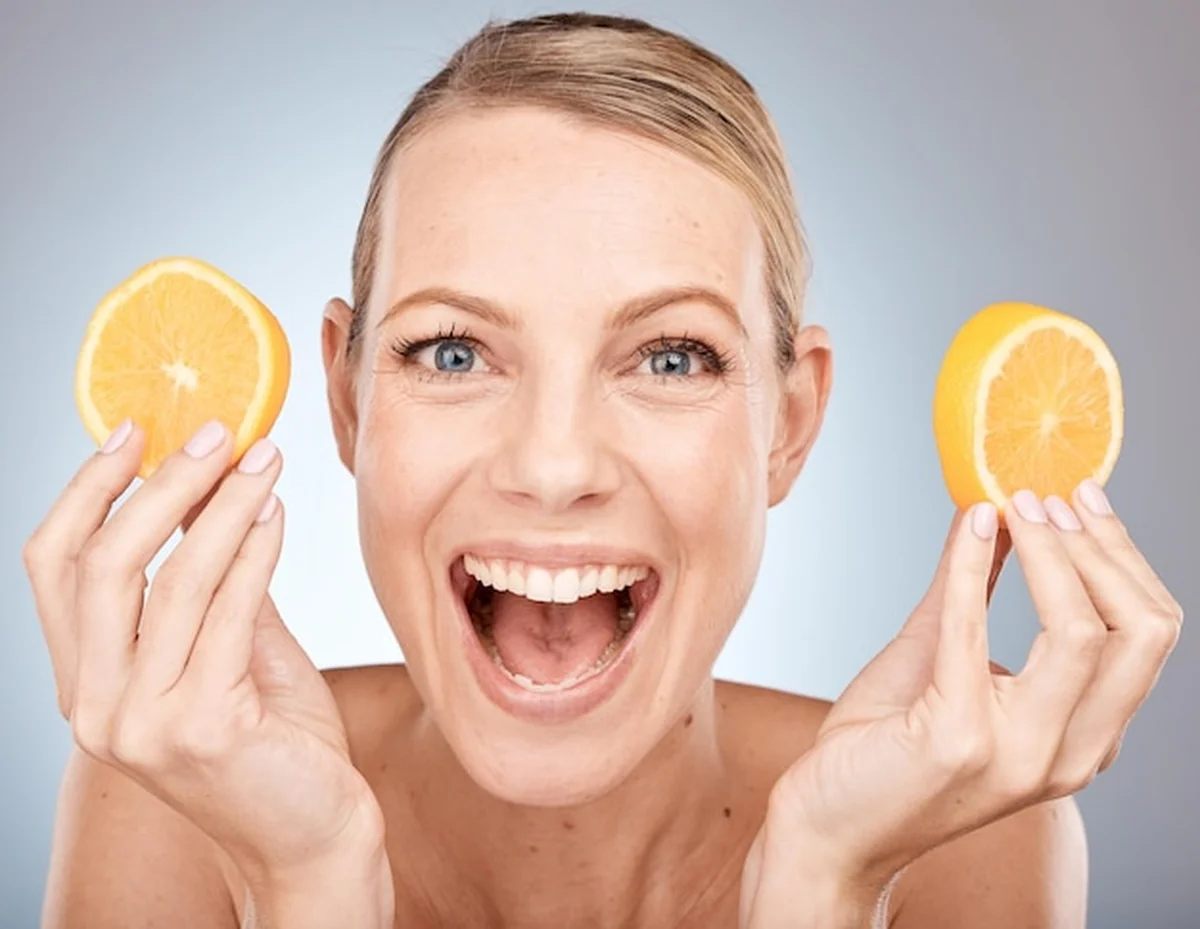 Kobieta trzymająca cytrynę przy twarzy do pielęgnacji skóry