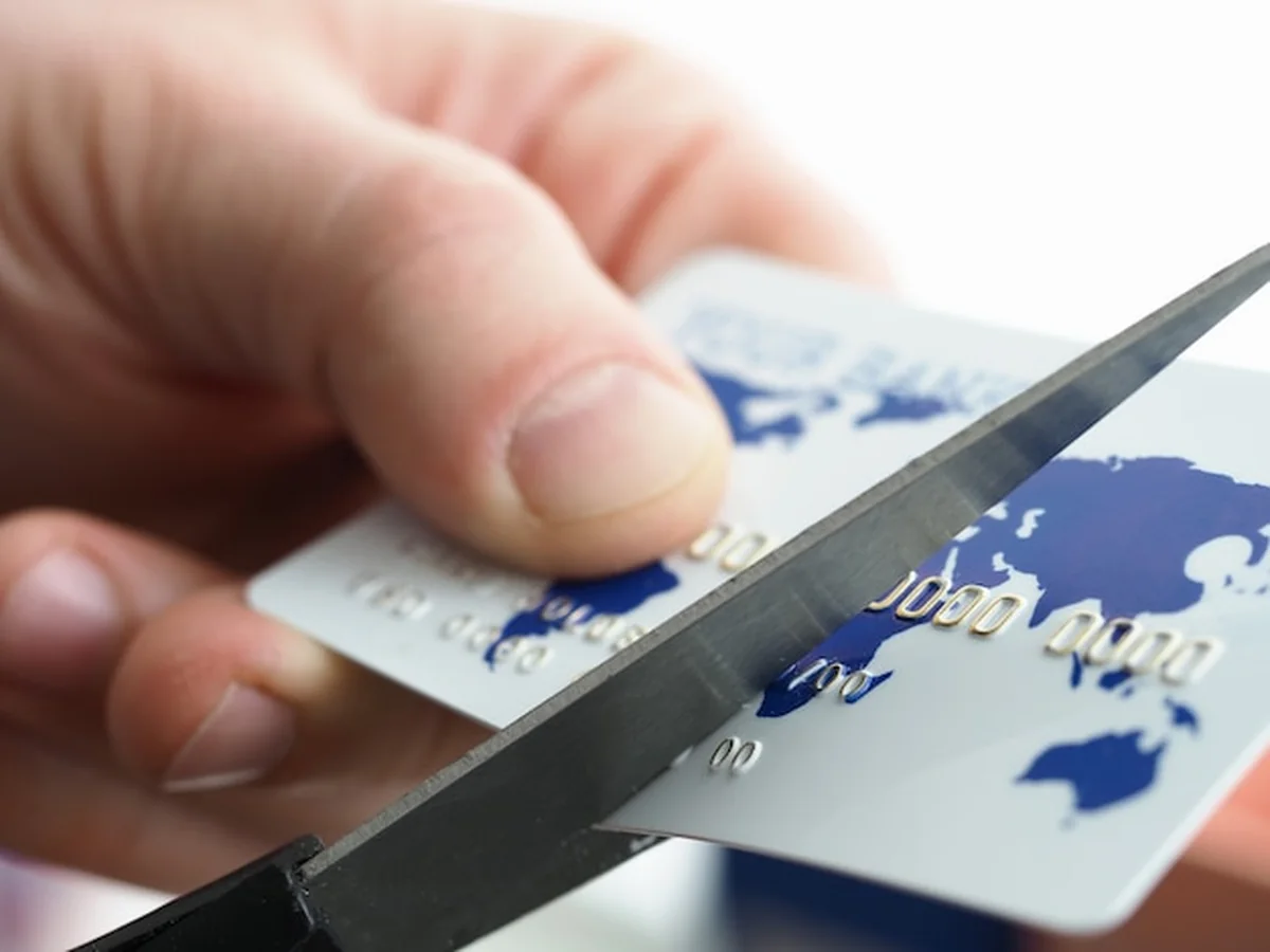 Biznesmen przecina kartę bankową nożyczkami