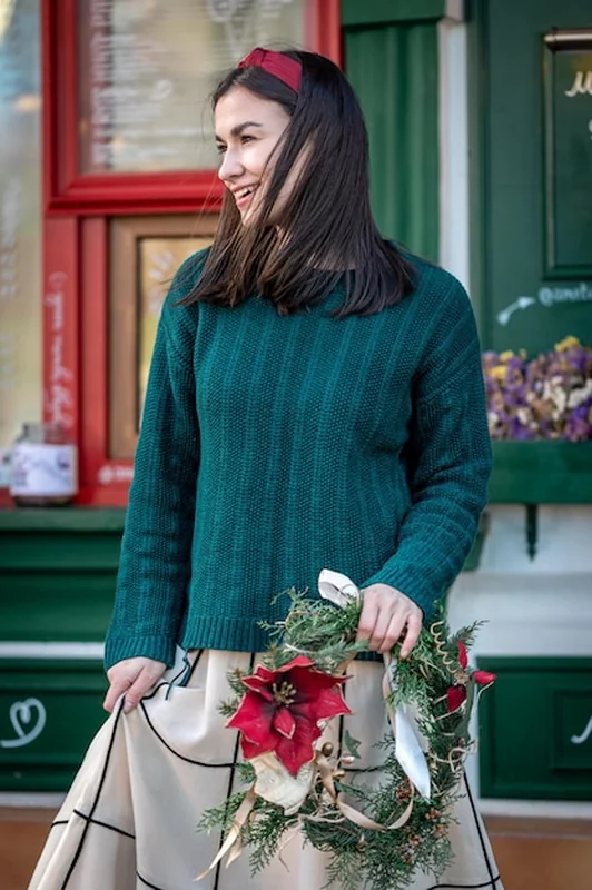 Młoda kobieta w żakardowym swetrze i bożonarodzeniowym wieńcu