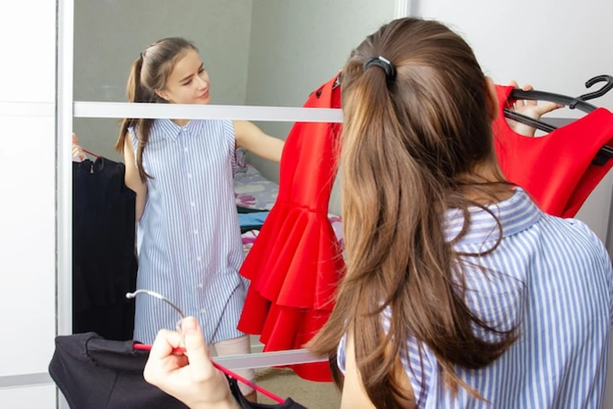 Dziewczyna w domu przymierza sukienkę przed lustrem