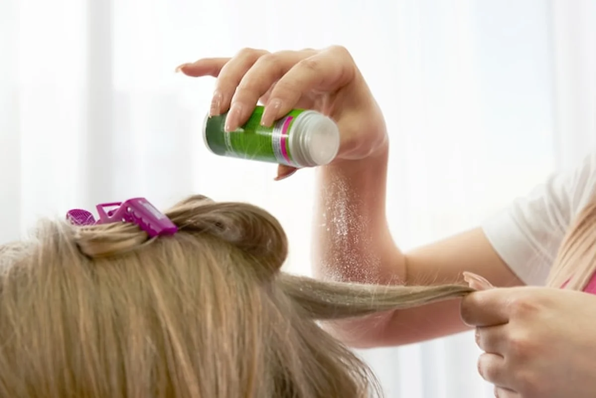 Fryzjer nakłada puder zwiększający objętość włosów klientki