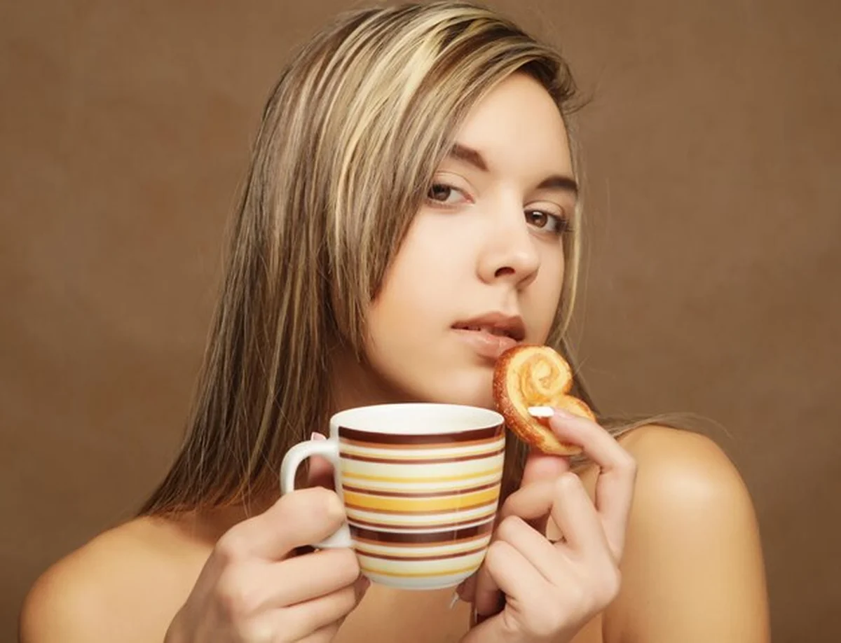 Młoda kobieta z filiżanką kawy na beżowym tle