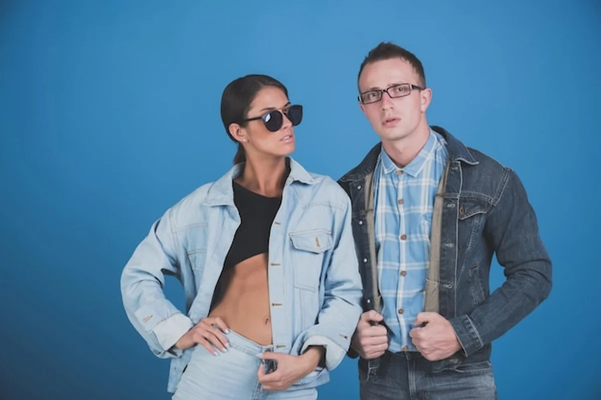 Moda stylowa kobieta i mężczyzna w okularach przeciwsłonecznych i kurtce jeansowej na niebieskim tle