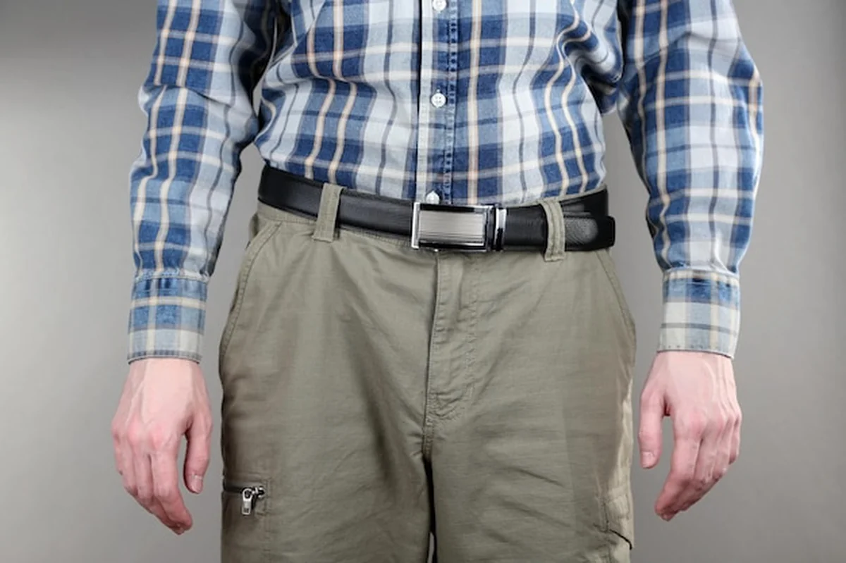 Mężczyzna w spodniach i koszuli na szarym tle