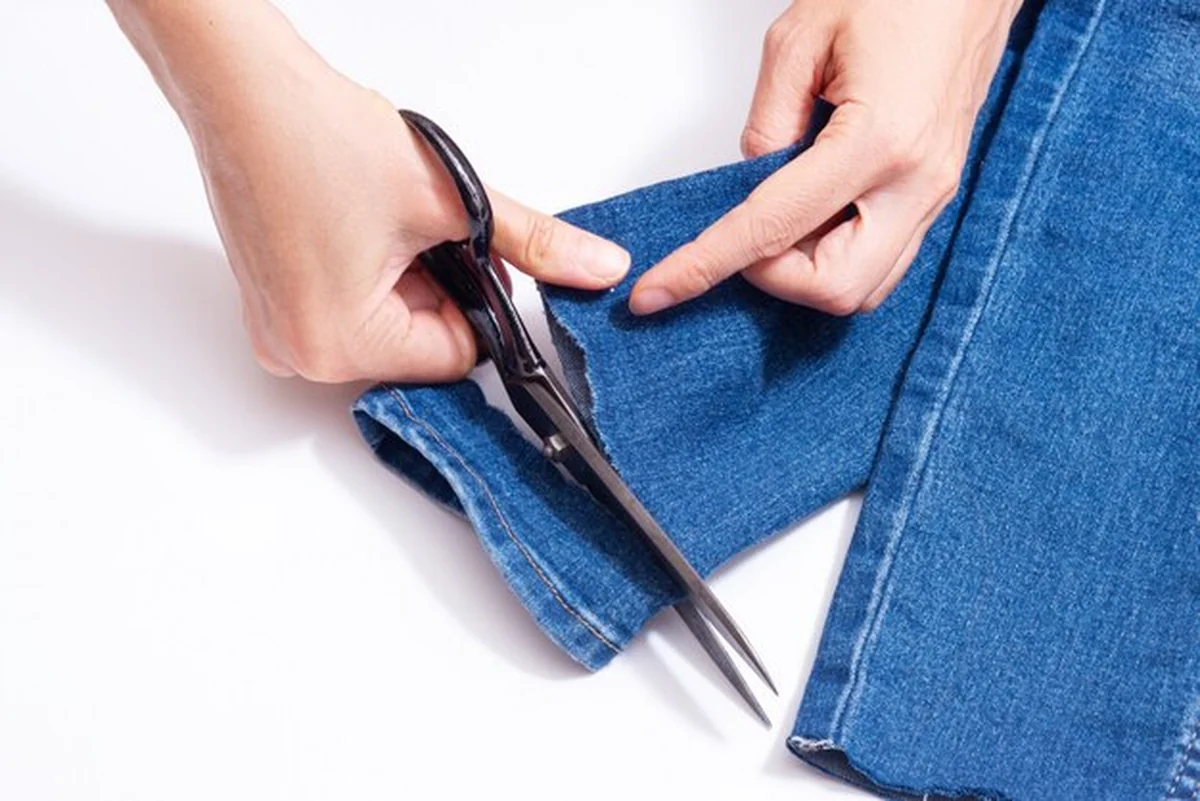 Kobieta skraca dżinsy nożyczkami