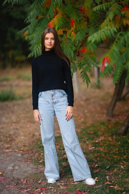 Piękna dziewczyna w dżinsach i czarnym golfie cieszy się naturą