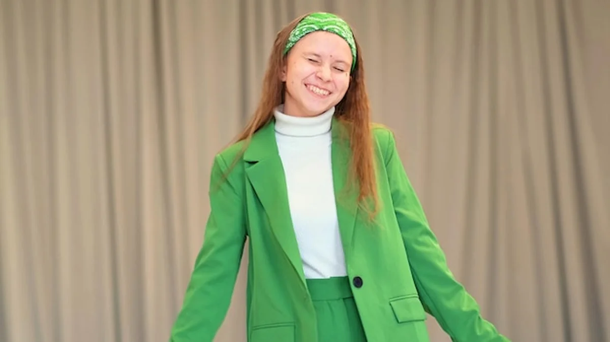 Młoda kobieta w zielonym garniturze uśmiecha się